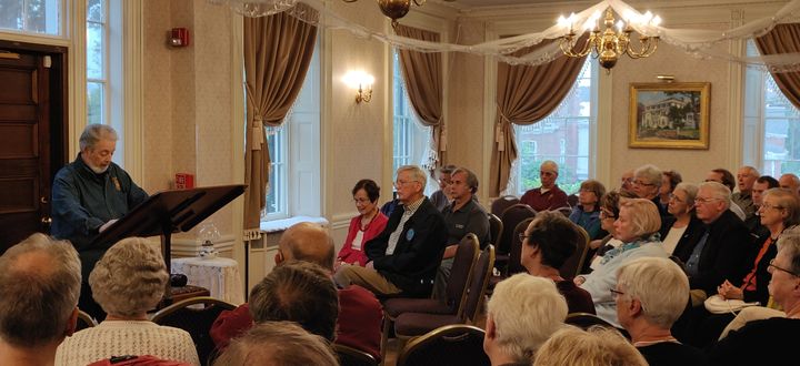 A man at a podium speaks to a large crowd.